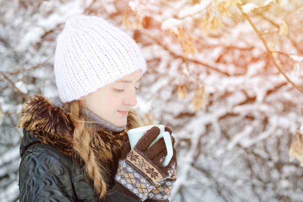 Menina em um chapéu branco no inverno com xícara de chá, vista lateral, close-up
 - Foto, Imagem