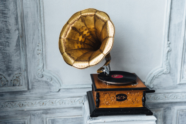 Old gramophone with horn speaker stands against anicent background, produces songs recorded on plate. Music and nostalgia concept. Gramophone with phonograph record - Photo, Image