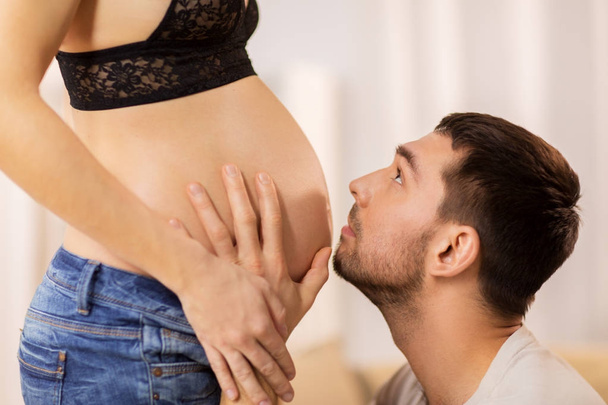妊娠中の女性の腹に触れる幸せな男 - 写真・画像