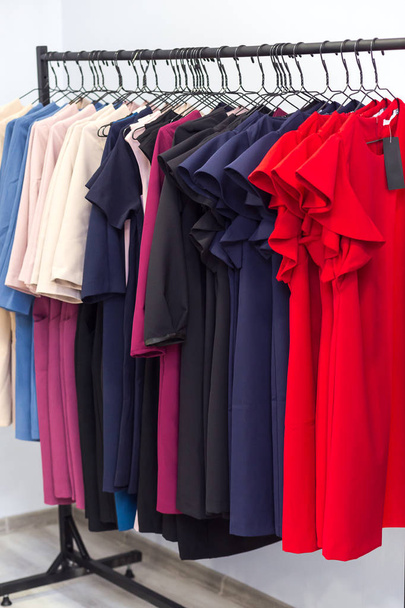farbenfrohe Frauenkleider und andere Kleidungsstücke auf Kleiderbügeln im Retail - Foto, Bild