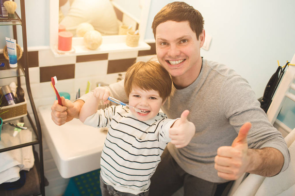 Young father with his son brushing teeth - 写真・画像