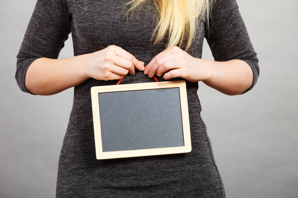Woman holding blank black board on stomach - Фото, изображение