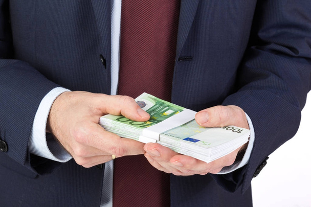 Деловой человек держит в руках деньги, банкноты евро
. - Фото, изображение