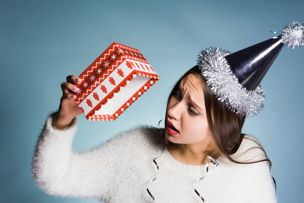 sad young girl in the cap received an empty box without a gift for the new year - Foto, immagini
