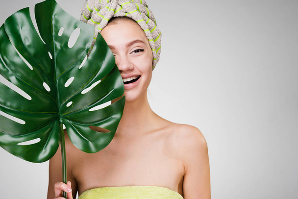 νεαρό κορίτσι με μια πράσινη πετσέτα για το κεφάλι, ημερήσιο σπα το γέλιο - Φωτογραφία, εικόνα