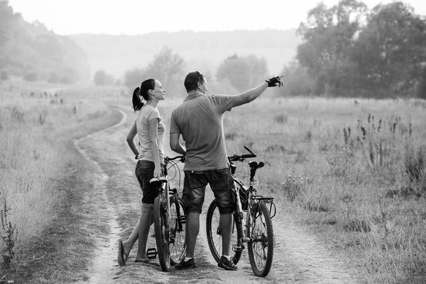 A fiatal pár, a kerékpárok területén. Fekete-fehér. - Fotó, kép