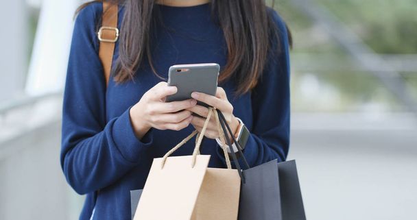 Woman using cellphone and holds shopping bags  - Photo, Image