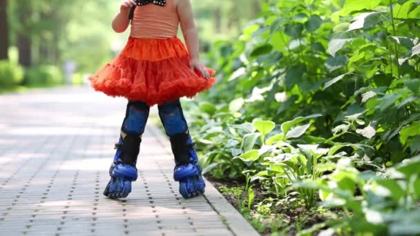 Beine eines kleinen Mädchens im Rock beim Rollschuhfahren im Park - Filmmaterial, Video