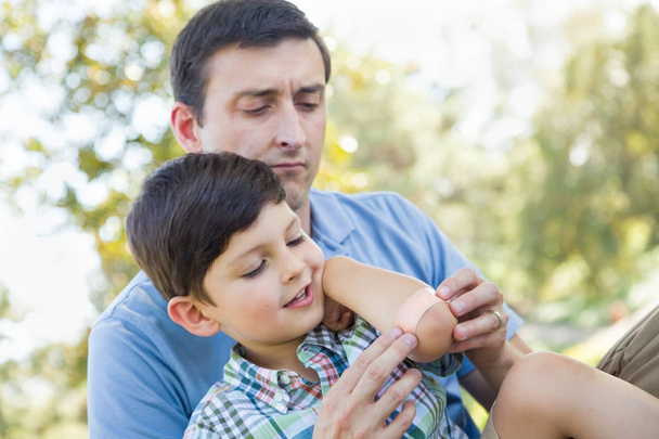Père aimant met un bandage sur le coude de son jeune fils dans le parc
. - Photo, image
