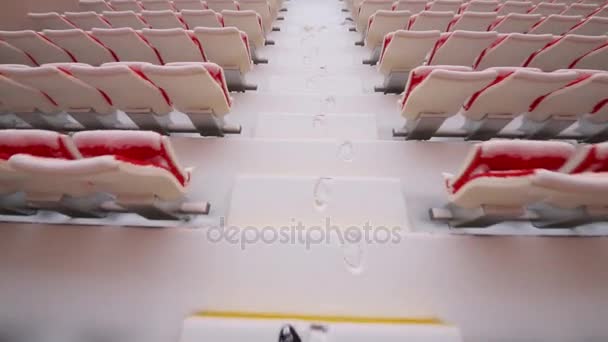 スタジアムのグランド スタンドの座席の間で雪に覆われた階段を男の足 - 映像、動画