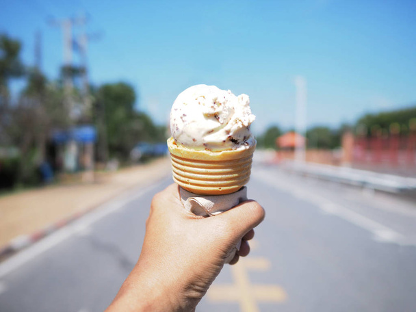 χέρι εκμετάλλευση τσιπ σοκολάτας παγωτό χωνάκι ζεστή μέρα του καλοκαιριού. - Φωτογραφία, εικόνα