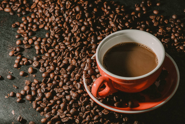 кофе в красной чашке и кофейная фасоль являются фоном
. - Фото, изображение