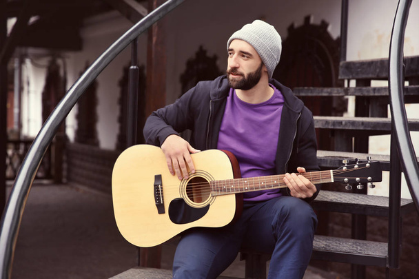 Young hipster man playing guitar outdoors - 写真・画像