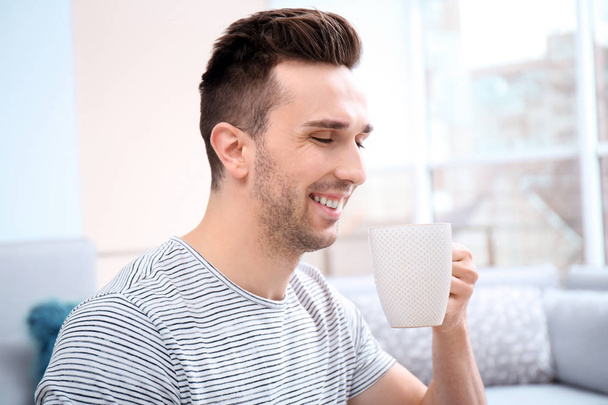 Handsome young man drinking coffee at home - Valokuva, kuva