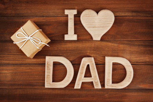 Привітання для День батька з фразою "Я тата любов" зроблені з букв і подарунок коробку на дерев'яними тлі - Фото, зображення
