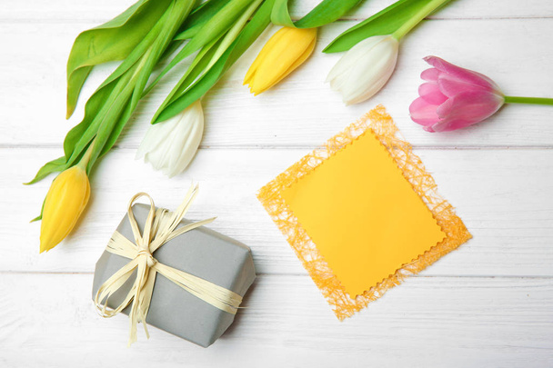Tulips, empty card and gift box on wooden background, top view - Fotó, kép