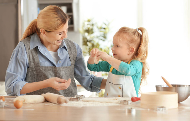 Mother and daughter with dough at table indoors - Foto, Bild