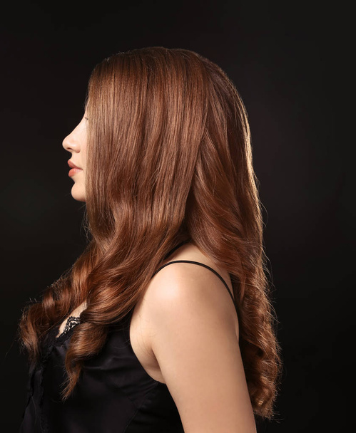 Young woman with caramel hair color on black background - Foto, Imagem