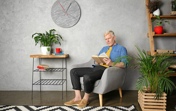 Attractive mature man reading book indoors - Foto, afbeelding