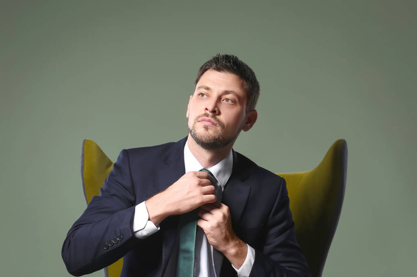 Handsome businessman sitting in comfortable armchair on color background - Foto, immagini