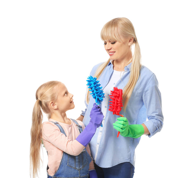 Little girl and her mother with cleaning supplies on white background - Foto, imagen