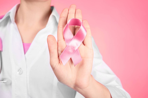 Arzt zeigt rosa Schleife auf farbigem Hintergrund. Brustkrebs-Aufklärungskonzept - Foto, Bild