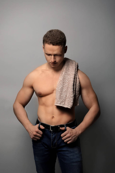 Muscular young bodybuilder with towel on grey background - Photo, image