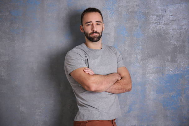 Portrait of handsome young man with crossed arms near color wall - Photo, Image