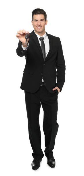 Salesman in formal suit holding car key on white background - Zdjęcie, obraz