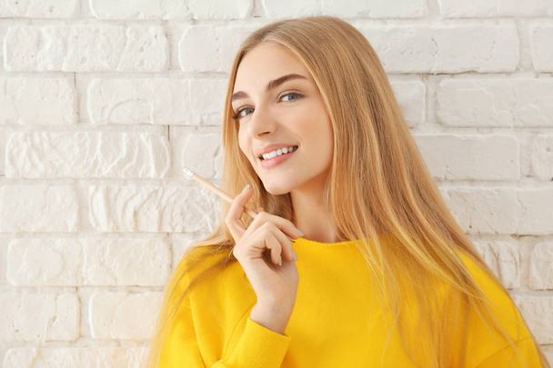 Smiling woman in yellow sweatshirt on brick wall background - Foto, immagini