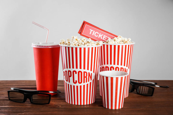 Tasty popcorn, glasses and tickets on wooden table - Фото, изображение