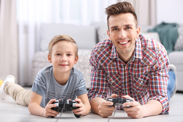 Cute little boy with father playing videogame at home - Foto, Bild
