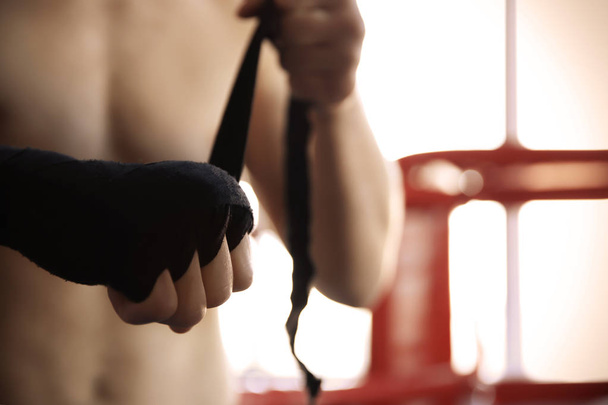 Young man wrapping hand with bandage in boxing ring - Foto, Imagem