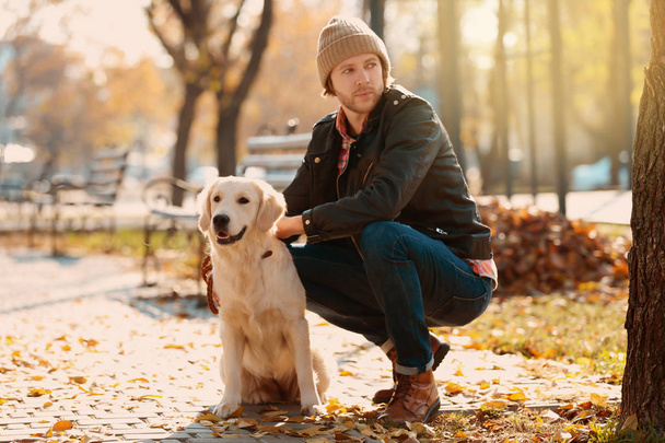 Handsome young hipster with dog outdoors - Fotó, kép