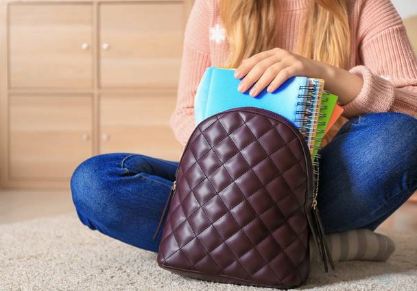 Woman putting notebooks into backpack at home - Foto, Imagen