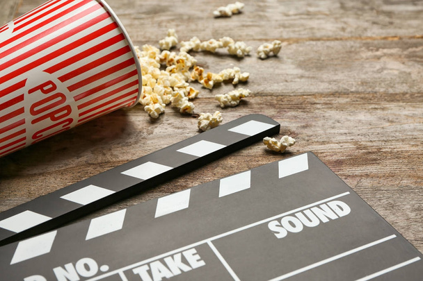 Movie clapper and popcorn on wooden background, closeup - Foto, Imagem