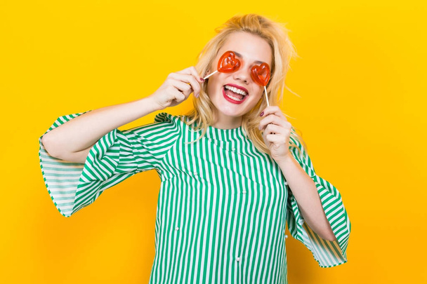 Portrait of beautiful young woman with lollipops on yellow background - Foto, Imagen