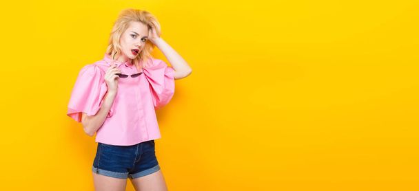 Portrait of stylish young woman in pink blouse posing on yellow background - Foto, immagini