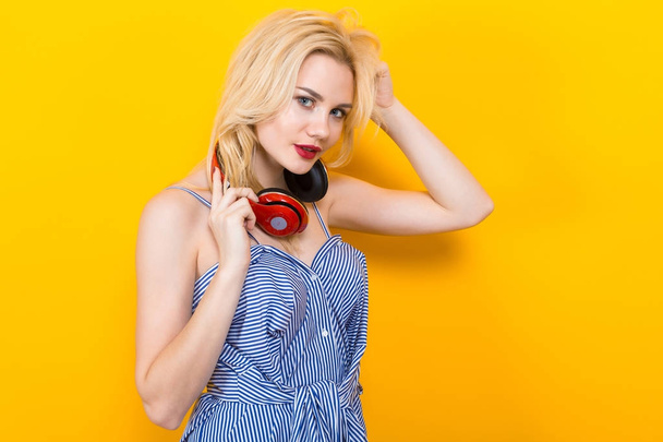 Mooie stijlvolle jongedame met rode koptelefoon op gele achtergrond - Foto, afbeelding