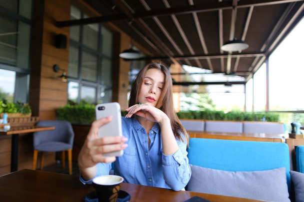Bájos lány, hogy selfie smartphone-val csésze kávé  . - Fotó, kép