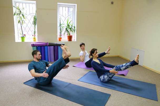 Giovane donna yoga trainer insegna il ragazzo e la ragazza a fare l'exer
 - Foto, immagini
