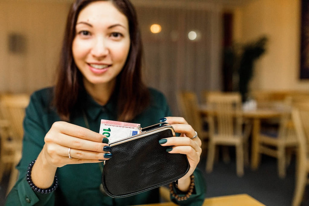 klant vrouw in het restaurant na het diner krijgt geld uit haar portemonnee om de rekening te betalen - Foto, afbeelding