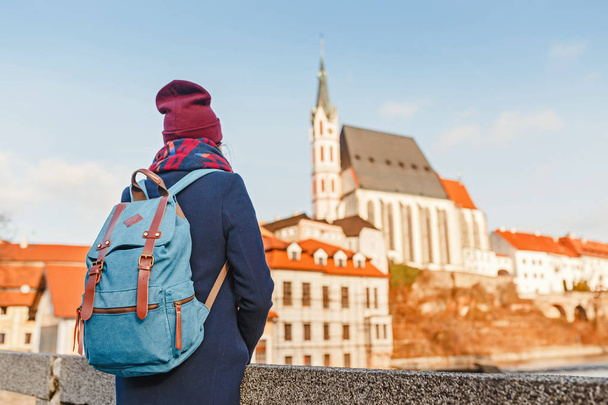 チェコ共和国で有名なチェスキー ・ クルムロフの街の素晴らしい景色を楽しみながらのバックパックと幸せな若い女性旅行者 - 写真・画像
