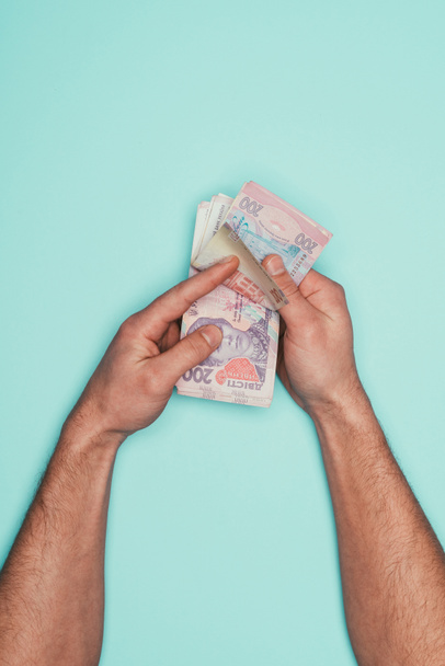 cropped shot of man counting cash isolated on turquoise - 写真・画像