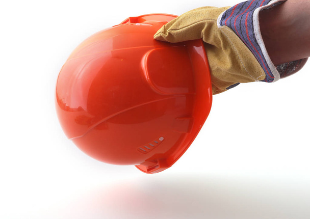worker in protective gloves holds an orange hard hat in his hand. Safety helmet. - Φωτογραφία, εικόνα