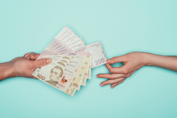 cropped shot of woman taking cash from man isolated on turquoise - Photo, Image