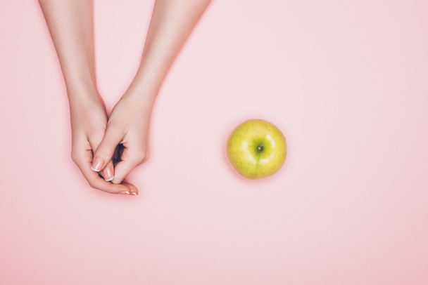 περικοπεί shot γυναίκα με το πράσινο μήλο που απομονώνονται σε ροζ - Φωτογραφία, εικόνα