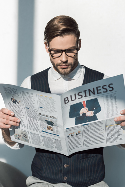portrait of stylish young businessman in eyeglasses reading newspaper - Photo, image