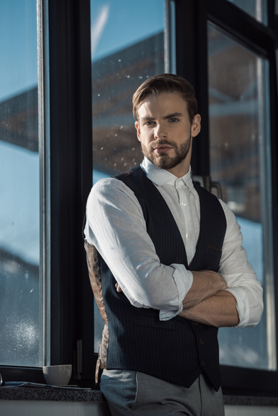 portrait of confident stylish young businessman standing with crossed arms and looking at camera - Fotografie, Obrázek