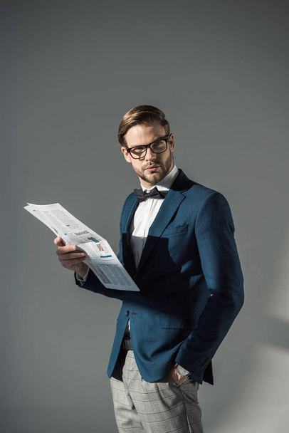 portrét pohledný módní podnikatel v brýlích čtení novin na grey - Fotografie, Obrázek